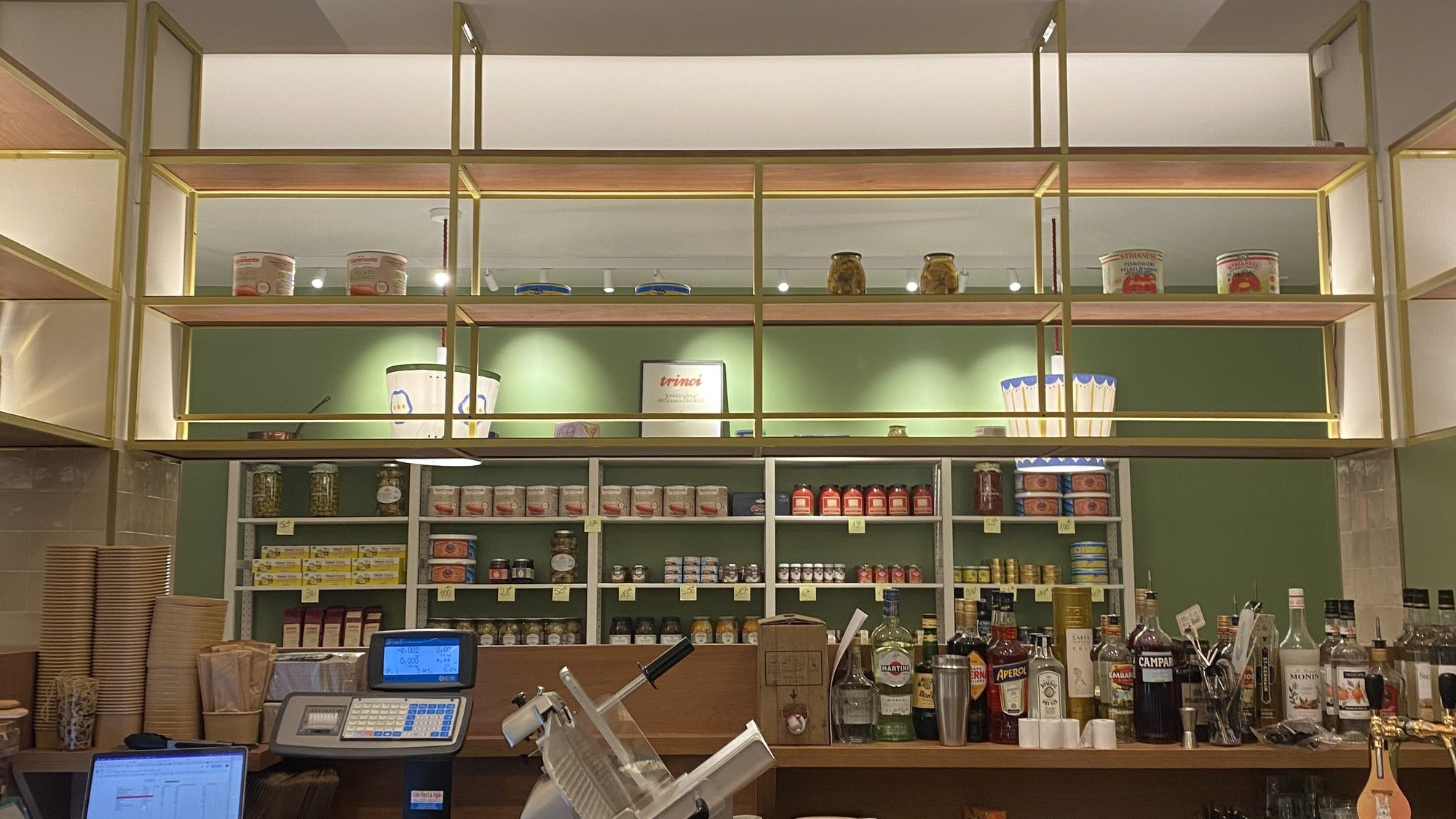 Le comptoir de l’épicerie fine italienne Toscanacci à Pantin, avec sa trancheuse à charcuterie et ses étagères de produits d’Italie