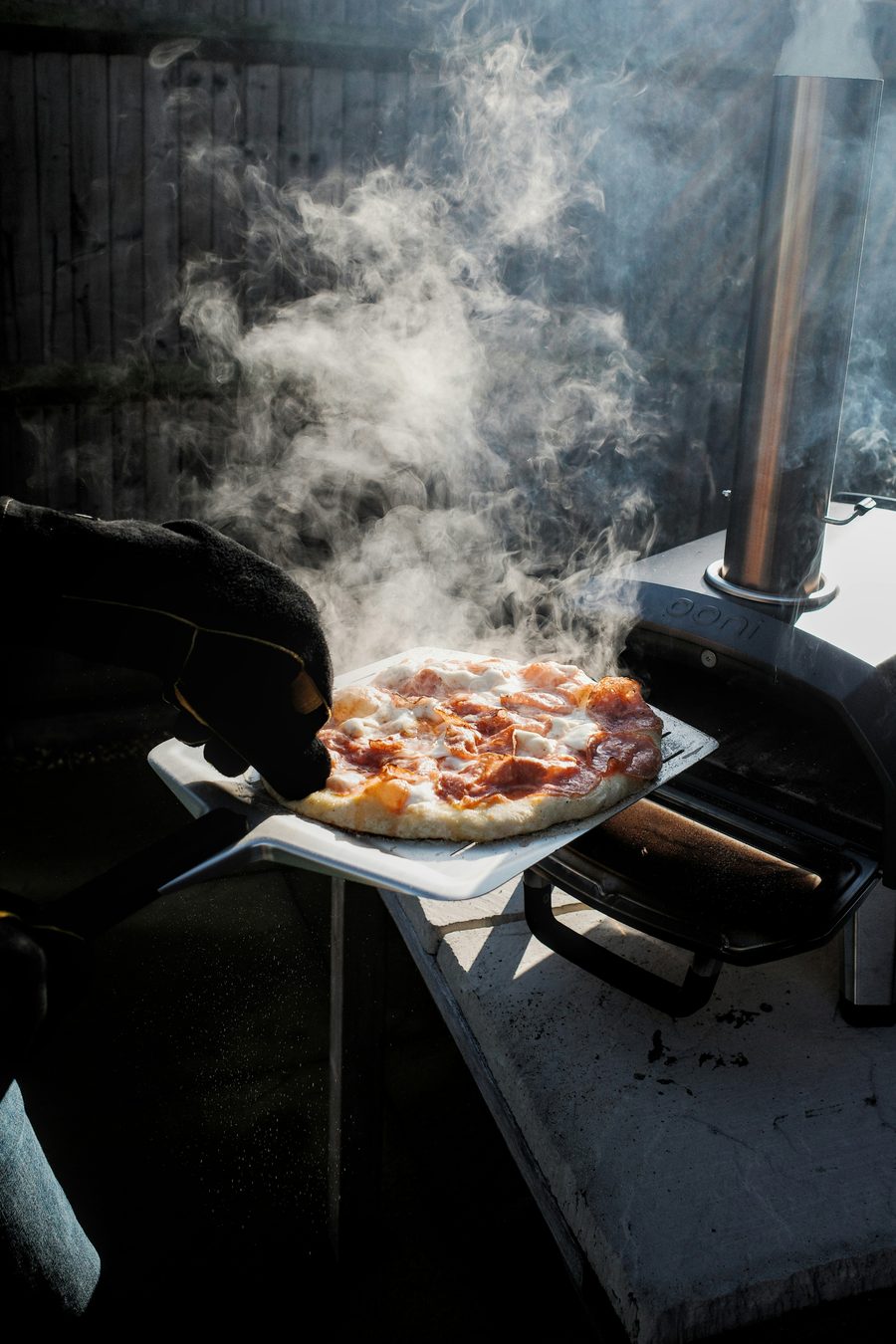 Pizza fumante tout juste sortie du four sur une pelle à pizza — le traiteur italien à domicile Toscanacci